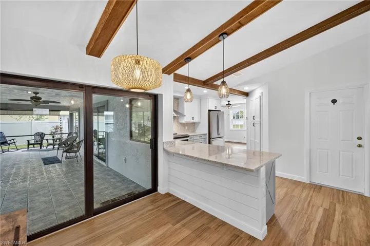 Kitchen with a ceiling fan, white cabinetry, light stone counters, decorative light fixtures, and light wood-type flooring