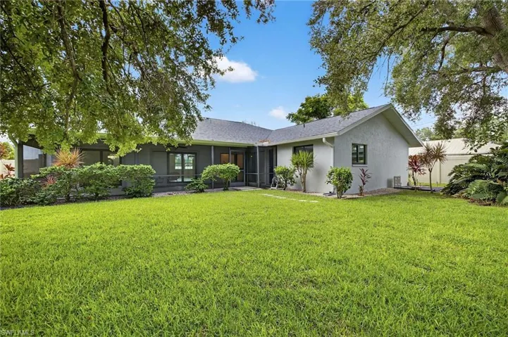 Ranch-style house with stucco siding, a sunroom, a front lawn, and a shingled roof