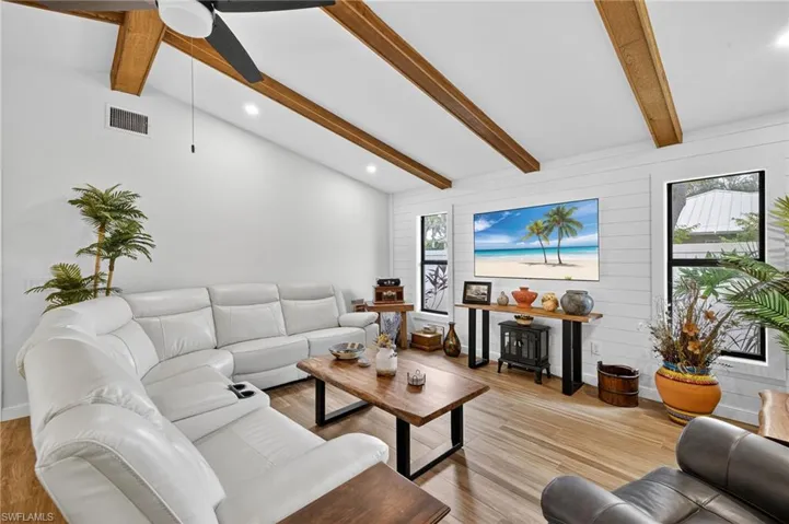 Living area with beamed ceiling, light wood-type flooring, high vaulted ceiling, recessed lighting, and ceiling fan