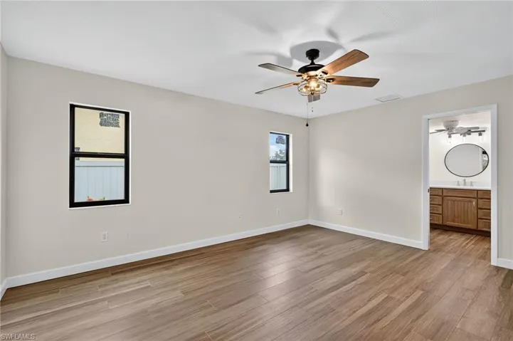 Unfurnished bedroom featuring light wood-style floors, a ceiling fan, and ensuite bath