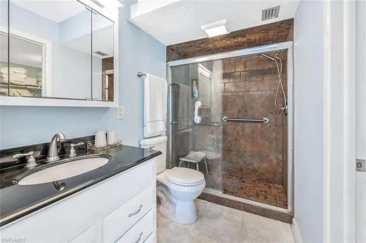 Bathroom featuring enclosed walkin shower, high vanity, and tile patterned flooring.