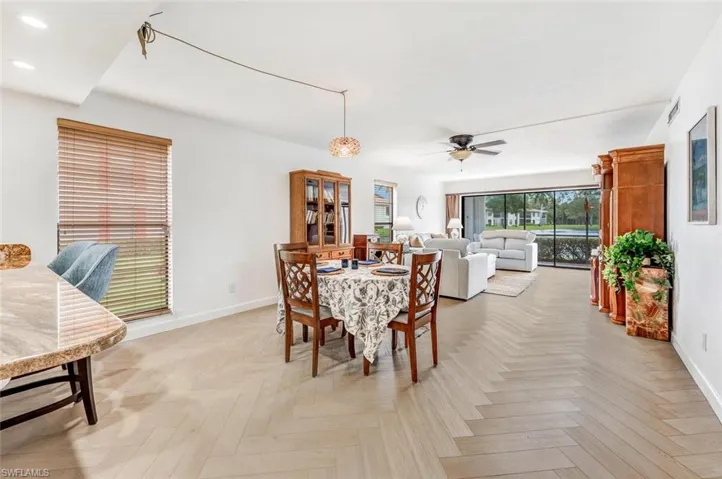 Dining area featuring ceiling fan and light parquet flooring installed as such a nice herringbone pattern.