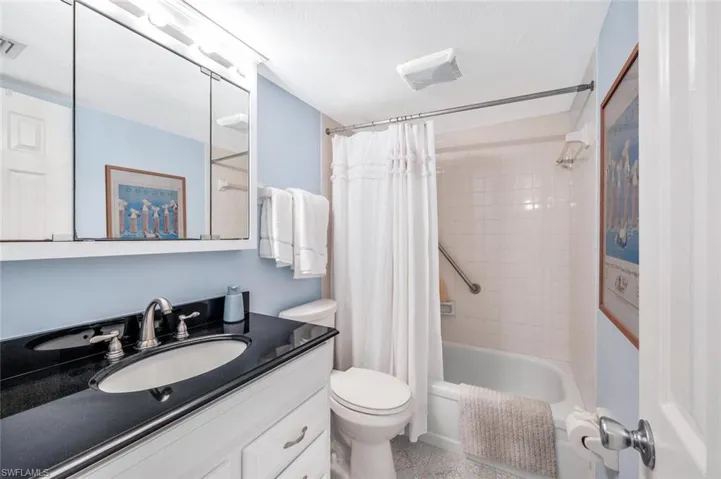 Full bathroom with shower / bath combo with shower, vanity, and tile patterned flooring, assistance bar.  Ample storage.