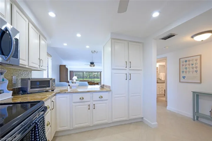 Notice how cheerful the kitchen is, with a passthrough to the dining area and the 2 stools at the counter.