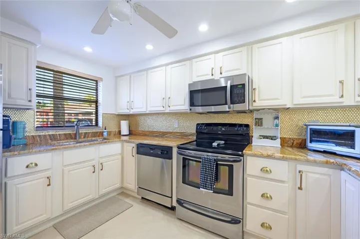 Kitchen with ceiling fan, stainless steel appliances, light stone countertops, tasteful backsplash, and microwave and more!