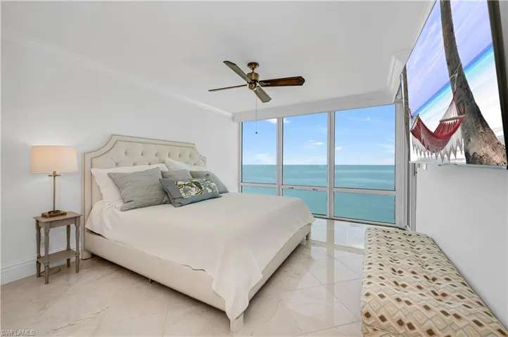 Bedroom featuring access to exterior, floor to ceiling windows, marble finish floor, and ornamental molding
