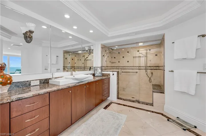 Primary bathroom with baseboards, ornamental molding, recessed lighting, a stall shower, and a raised ceiling