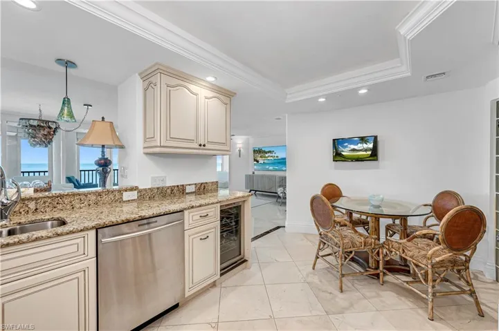 Kitchen with dishwasher, a raised ceiling, cream cabinets, and a sink