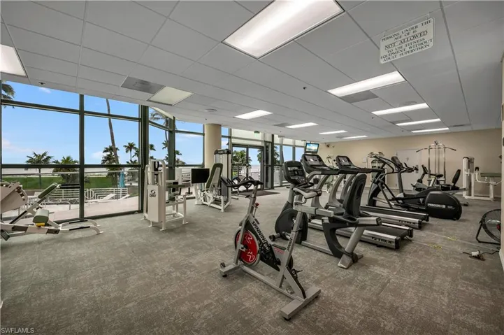 Exercise room featuring a wealth of natural light, expansive windows, and a drop ceiling