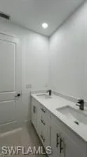Dual vanity with integrated sinks, white countertops, black faucets, and recessed lighting
