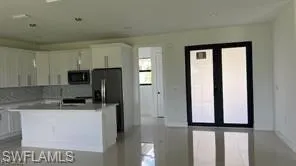 Open-concept living area with a white kitchen featuring stainless steel appliances, a center island, and a tiled backsplash