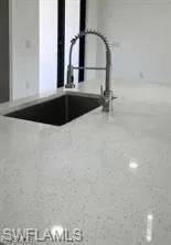 White countertop with integrated undermount sink and a modern gooseneck pull-down faucet
