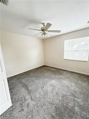 Spacious room featuring neutral wall tones and plush grey carpeting