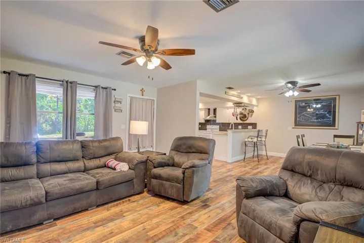 Living area with light wood-style flooring, visible vents, and a ceiling fan