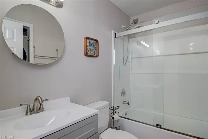 Bathroom with shower / bath combination with glass door, vanity, and toilet