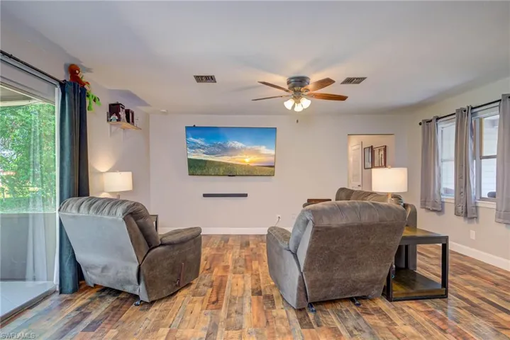 Living room with visible vents, ceiling fan, baseboards, and wood finished floors