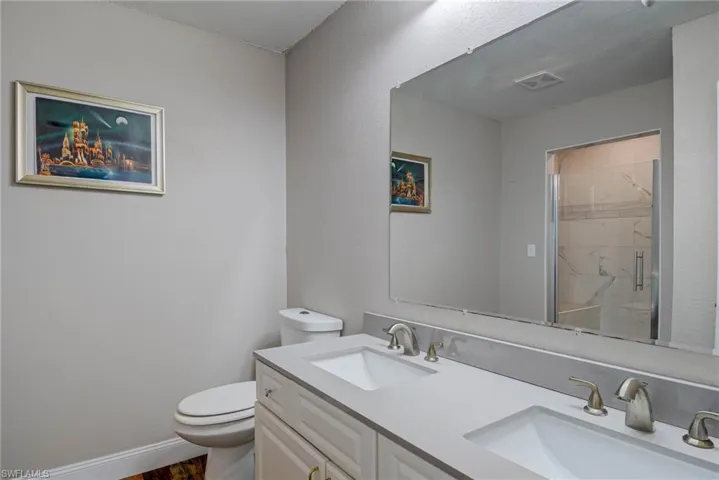 Bathroom with toilet, a sink, a shower stall, and visible vents