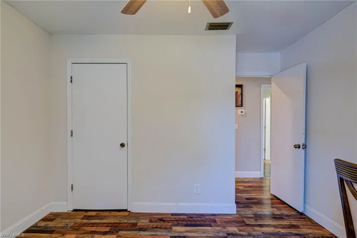Unfurnished bedroom featuring dark wood-type flooring, ceiling fan, baseboards, and visible vents