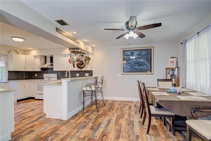 Dining room with wood finished floors, visible vents, a ceiling fan, and plenty of natural light