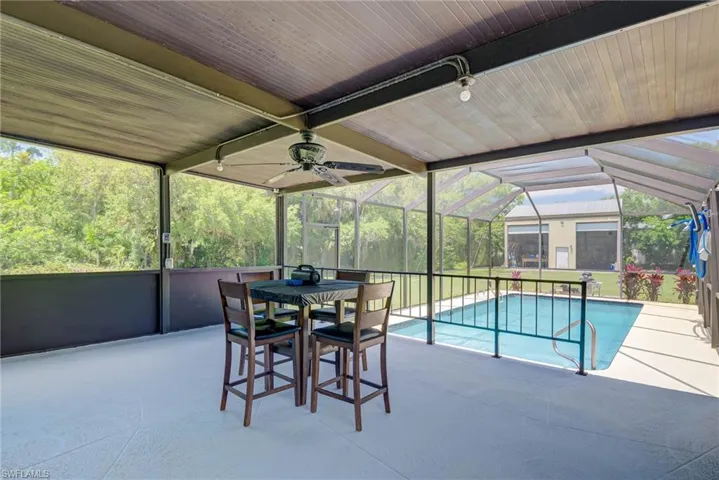 Outdoor pool with ceiling fan, glass enclosure, and a patio