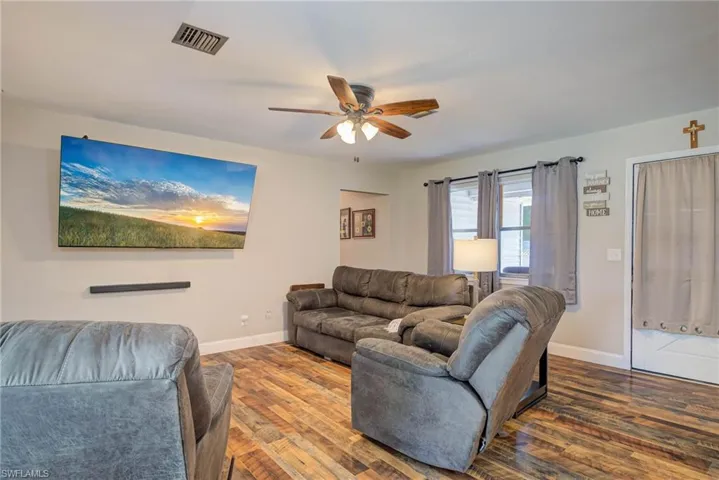 Living room featuring wood finished floors, baseboards, and a ceiling fan
