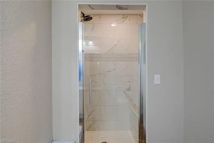 Bathroom featuring a textured wall and a stall shower