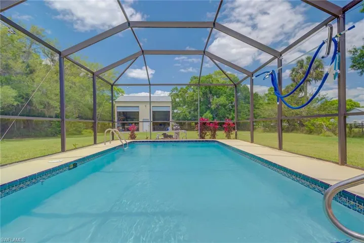 Outdoor pool featuring a patio area, glass enclosure, and a lawn