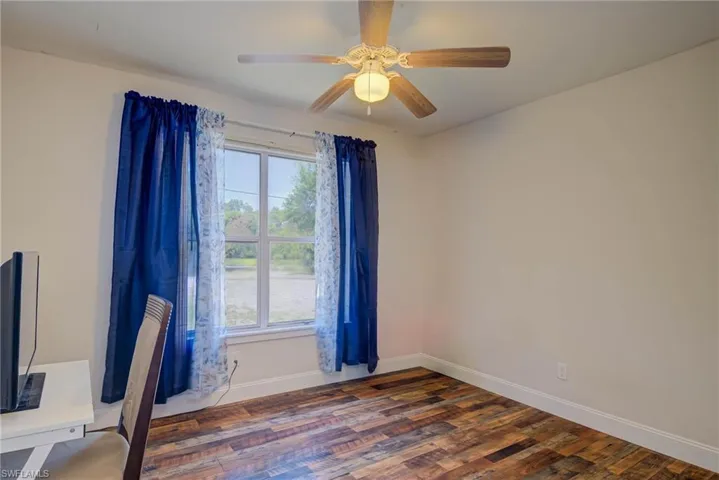 Unfurnished office featuring baseboards, a ceiling fan, and wood finished floors