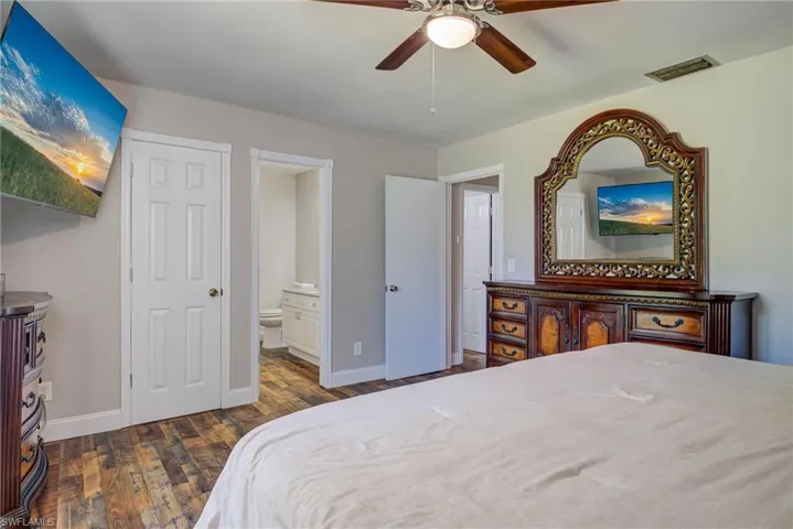 Bedroom featuring visible vents, baseboards, a ceiling fan, connected bathroom, and wood finished floors