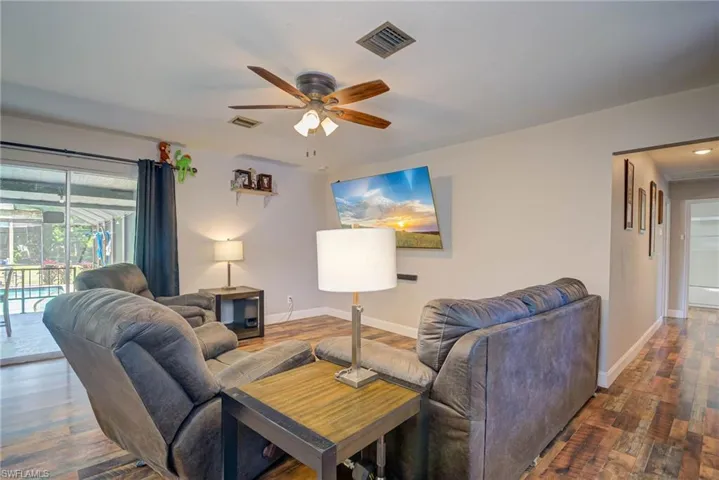 Living room featuring wood finished floors, ceiling fan, baseboards, and visible vents
