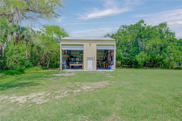 Back of property with an outbuilding, a detached garage, a pole building, and a lawn