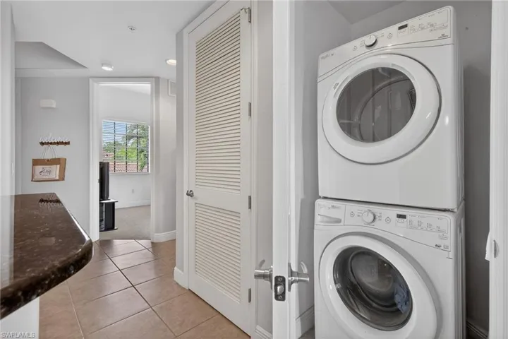 Laundry area featuring stacked washer / drying machine, light tile patterned flooring, and recessed lighting