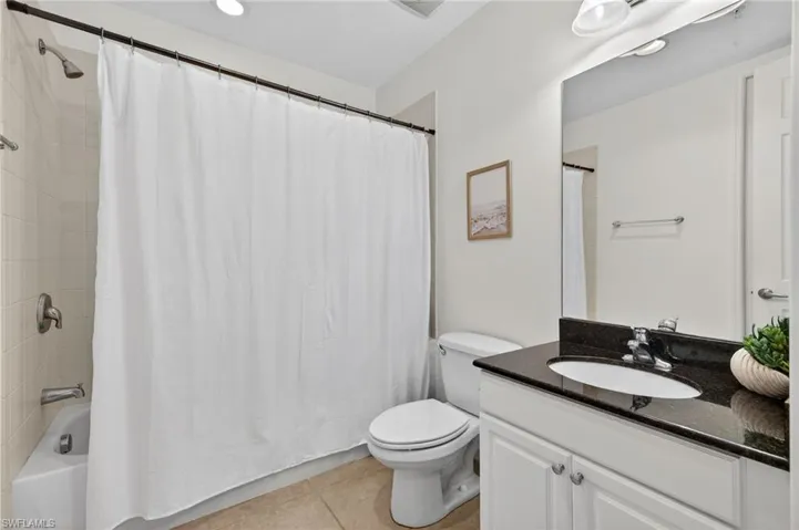 Bathroom with vanity, light tile patterned floors, and shower / bathtub combination with curtain
