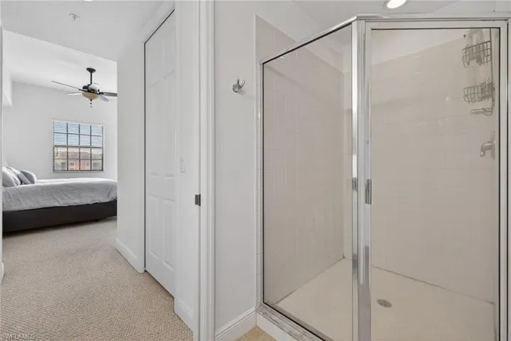 Full bathroom with a stall shower, light colored carpet, connected bathroom, and ceiling fan