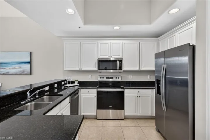 Kitchen featuring stainless steel appliances, white cabinetry, recessed lighting, dark stone counters, and light tile patterned floors