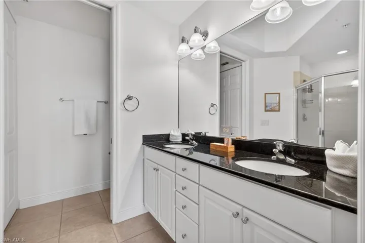 Full bath featuring double vanity, a stall shower, and light tile patterned flooring