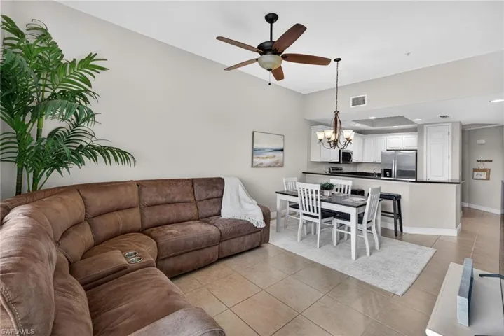 Living area featuring a ceiling fan, hanging lights, and light tile patterned floors
