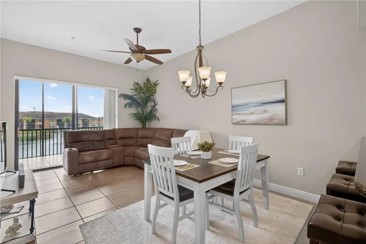 Dining area with a ceiling fan, hanging lights, lofted ceiling, and light tile patterned floors