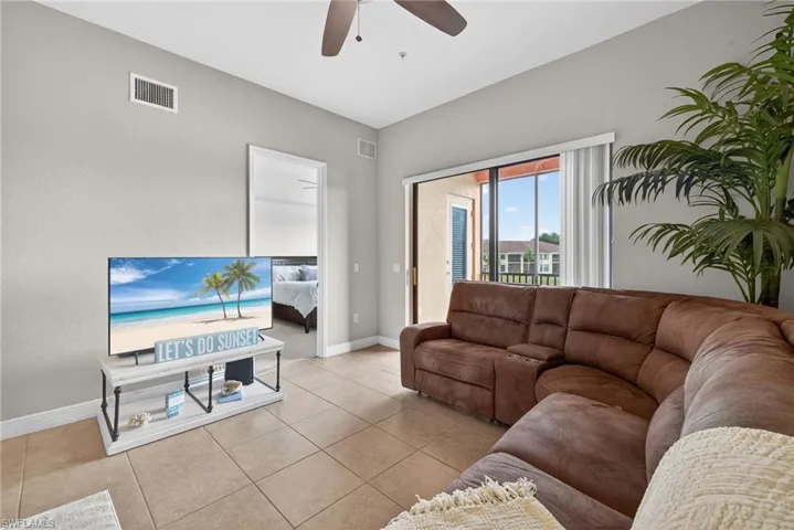 Living area featuring ceiling fan and light tile patterned flooring