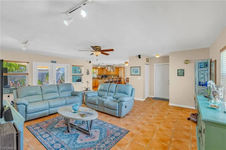 Living room featuring rail lighting, light tile patterned flooring, ceiling fan, and french doors