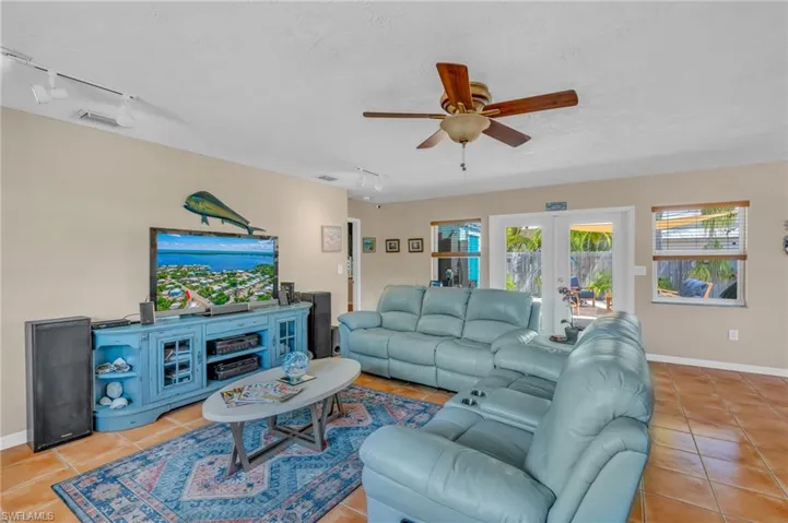 Living room featuring ceiling fan, light tile patterned floors, french doors, and track lighting