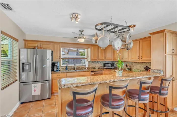 Kitchen with appliances with stainless steel finishes, kitchen peninsula, light tile patterned floors, ceiling fan, and sink