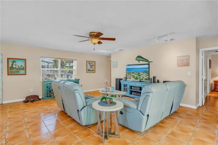 Tiled living room featuring ceiling fan and track lighting