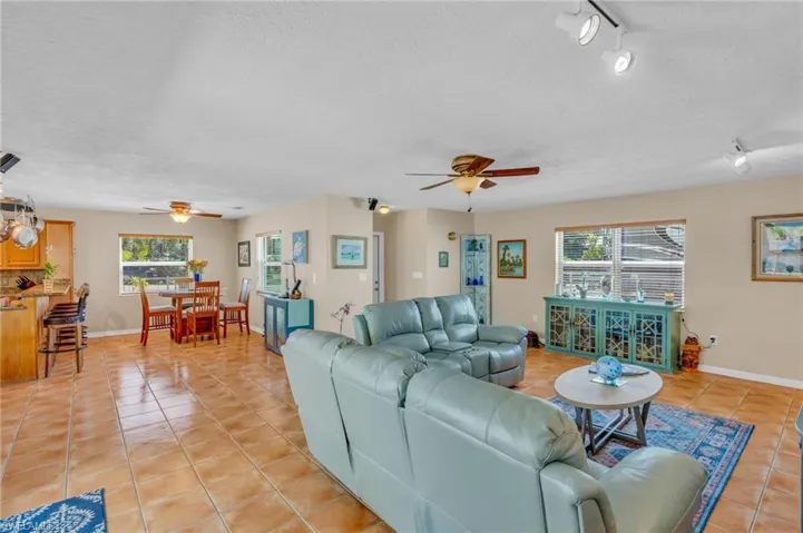 Living room with ceiling fan, light tile patterned flooring, and plenty of natural light