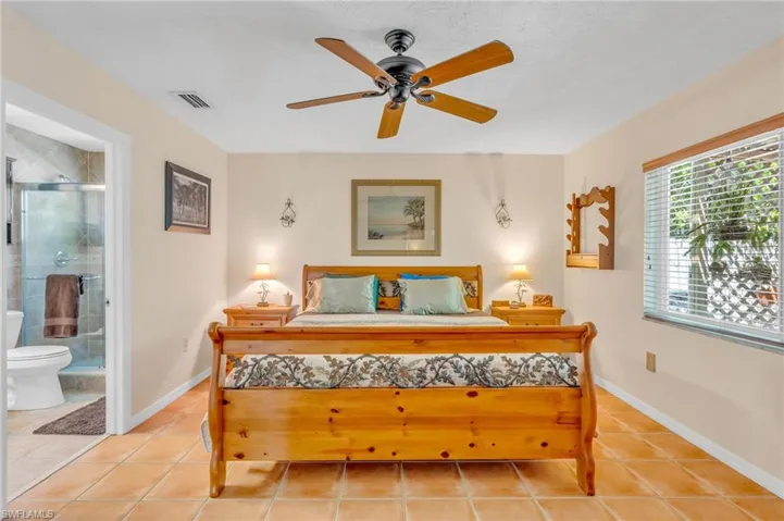 Bedroom with ceiling fan, ensuite bath, and light tile patterned floors
