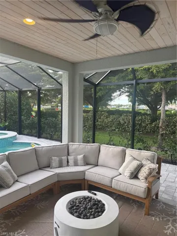Sunroom / solarium with ceiling fan, a hot tub, and an outdoor living space with a fire pit