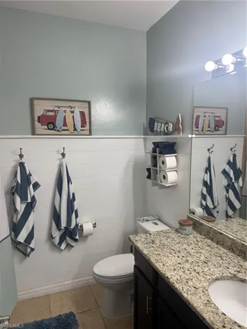 Bathroom featuring light tile patterned flooring, vanity, a wainscoted wall, and tile walls
