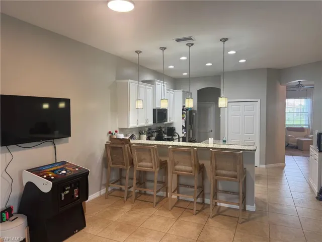 Kitchen with a breakfast bar area, white cabinetry, ceiling fan, hanging light fixtures, and recessed lighting