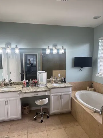 Bathroom featuring a bath, light tile patterned flooring, and double vanity