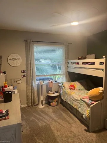 Bedroom with dark carpet and a ceiling fan